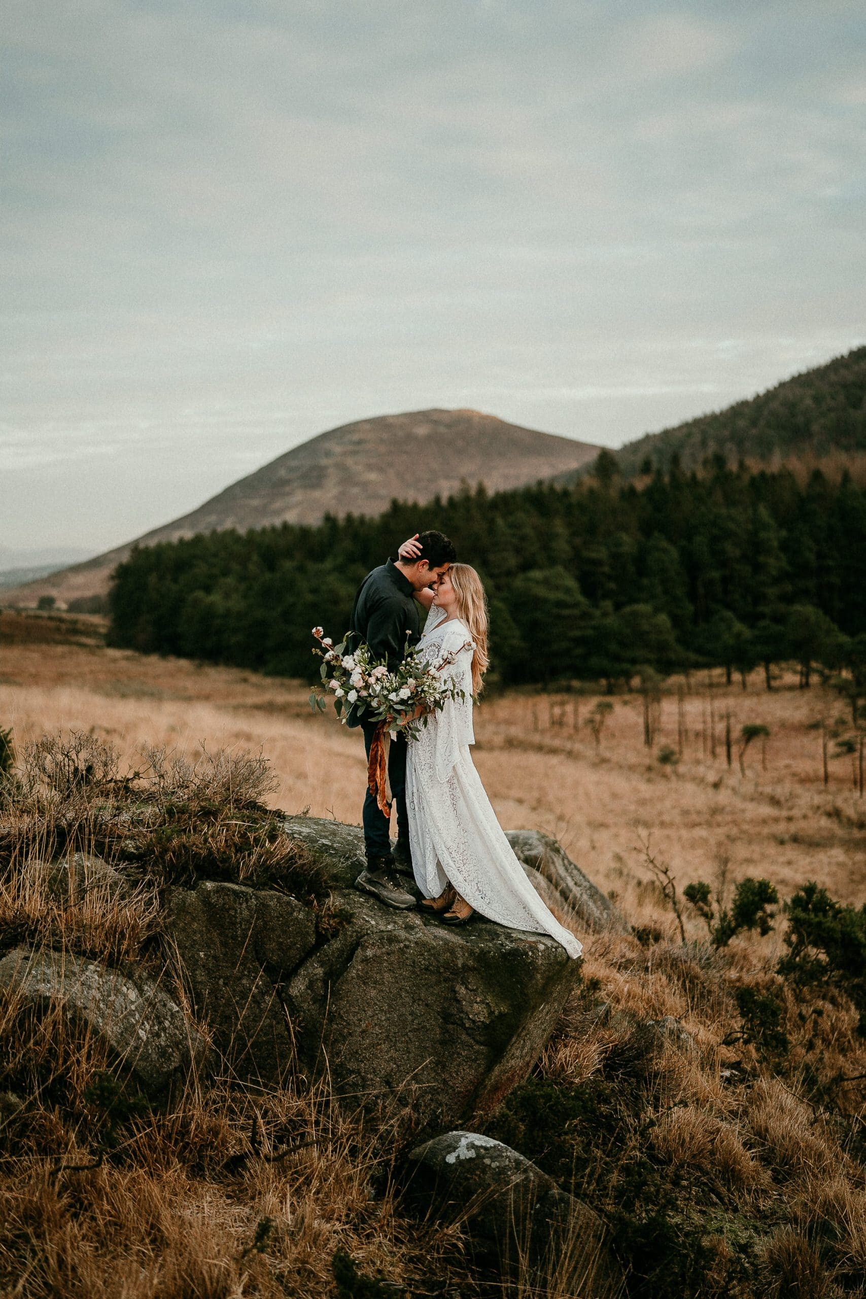 Gorgeous elopement photo of a bride and groom in the Irish mountains. Huge bouquet and a boho  reclamation dress. Wedding dress. Adventure elopements in Ireland. 