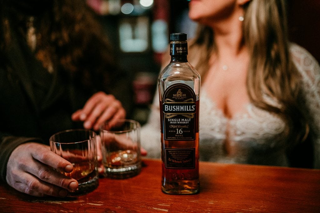 A bottle of Bushmills Whiskey with a bride and groom.