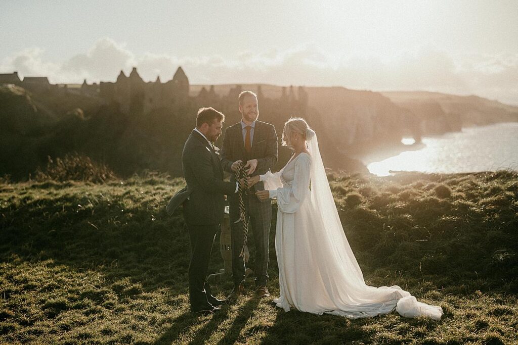 An american couple getting married at Dunluce Castle in Northern Ireland. They are doing the handfasting ritual.