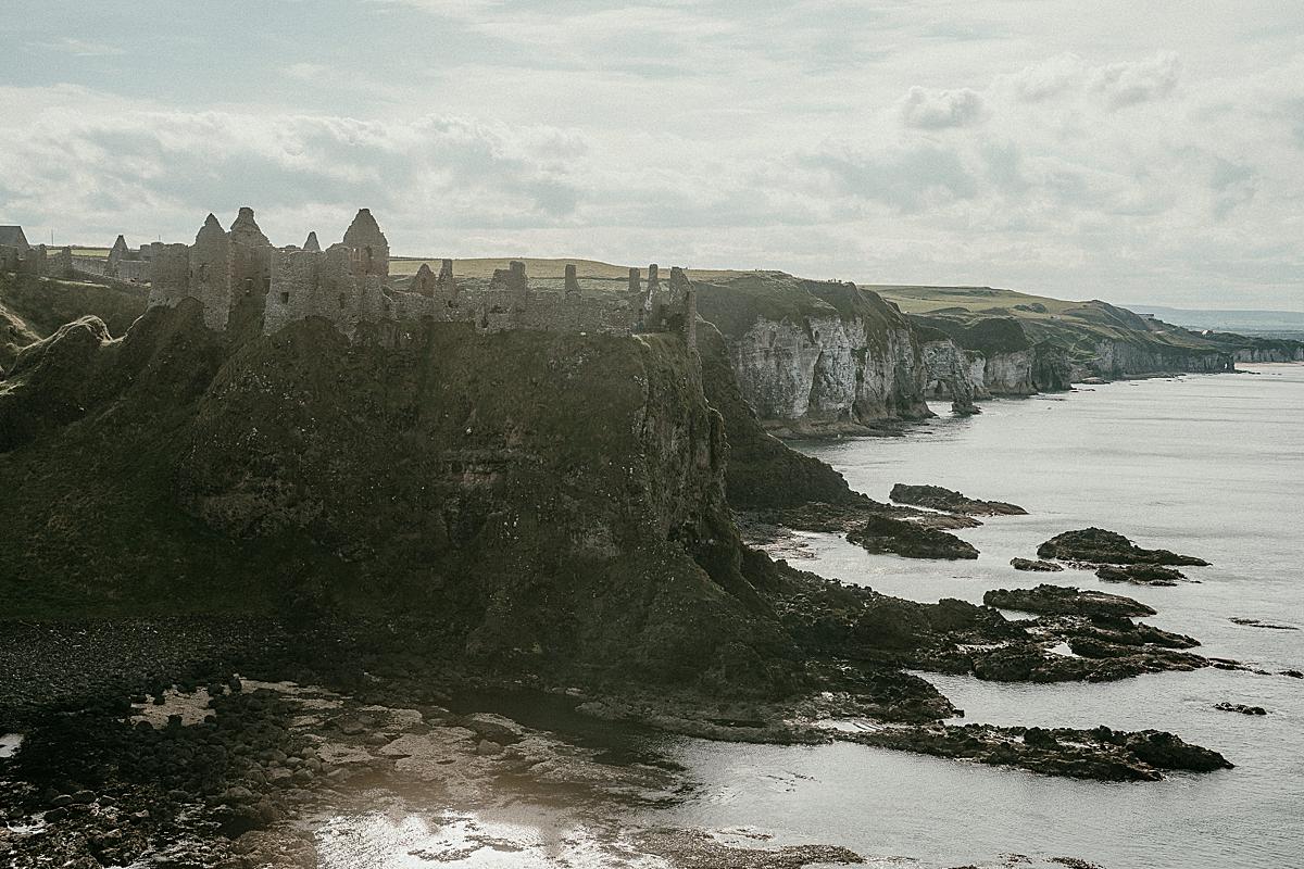 Dunluce Castle on a sunny day with clouds in the sky.