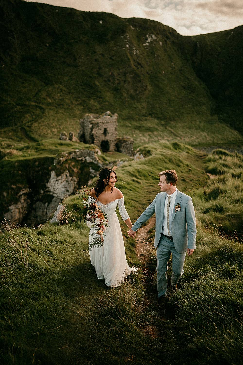 A bride & groom walking on the headland at Kinbane Castle on their elopement day in Northern Ireland.