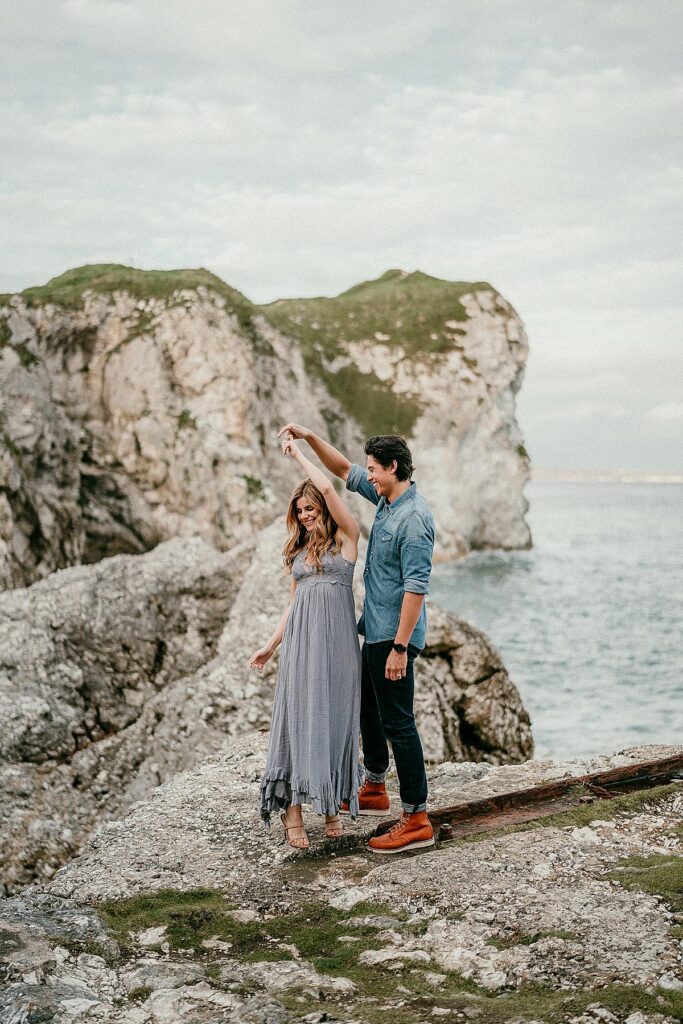 Jordan Connor from Netflix show Riverdale dancing with his wife during their engagement session at Kinbane Castle in Northern Ireland. The white cliffs are in the background.